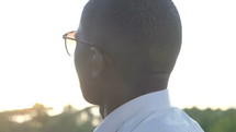 a young man in glasses standing outdoors 