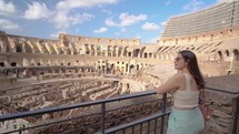 A beautiful woman tourist visiting inside the Coliseum. Happy moments of travel in ancient roman architecture in rome italy.
