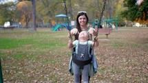 mother pushing her daughter on a swing set 