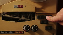 A hand push play/stop button on vintage tape reel recorder.