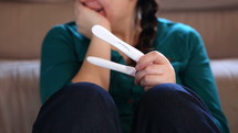 a smiling woman looking at positive pregnancy tests 