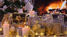 Gifts under the Christmas tree in front of fireplace with lights and burning candles. Christmas giving concept. 