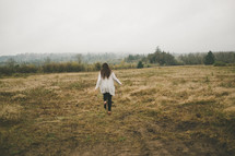 A woman runs through a meadow.