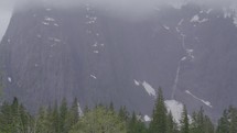 Tilt up of foggy mountain with snow and waterfall