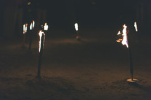 Burning torches stuck into the ground.