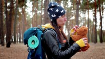 Young woman hiking nature in pine forest. Happy tourist with backpack on forest pine trees. Hipster woman hiker in forest a park. Adventure travel ecotourism concept. Lifestyle travel in nature.