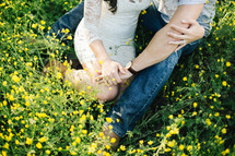 a couple sitting in a meadow of yellow flowers 