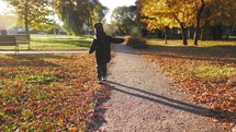 Cute boy walking in the autumn park. Boy walking and keeps balance in the autumn nature.