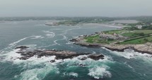 Drone flying at coast with waves and big houses
