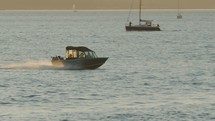 Speedboat moves across water quickly with sailboats in the background, slow-motion