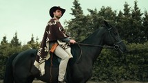 Cowboy rides a black horse in the nature