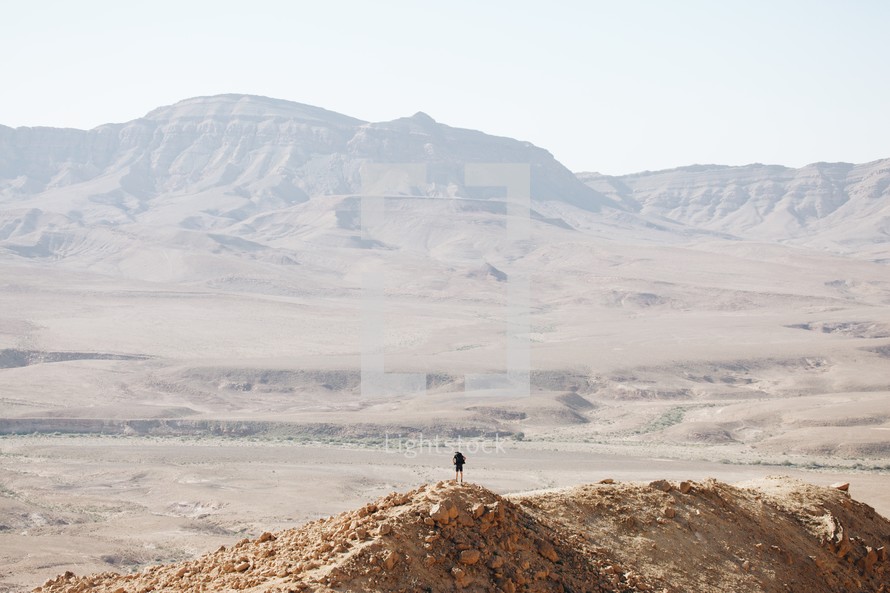A man hiking alone on top of a mountain in the hot desert wilderness of the Maktesh in Israel