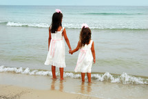 sisters holding hands on a beach 