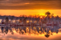 reflection of an orange sky at sunset over pond water 
