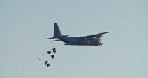 Transport plane dropping cargo packs with parachutes