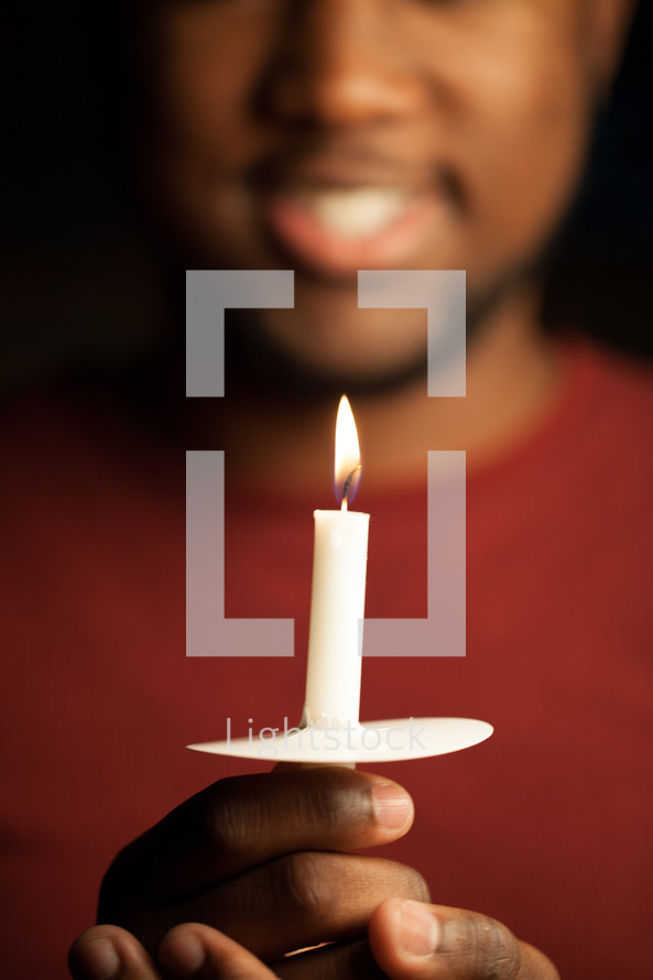 An African American man holding a candle at a worship service 