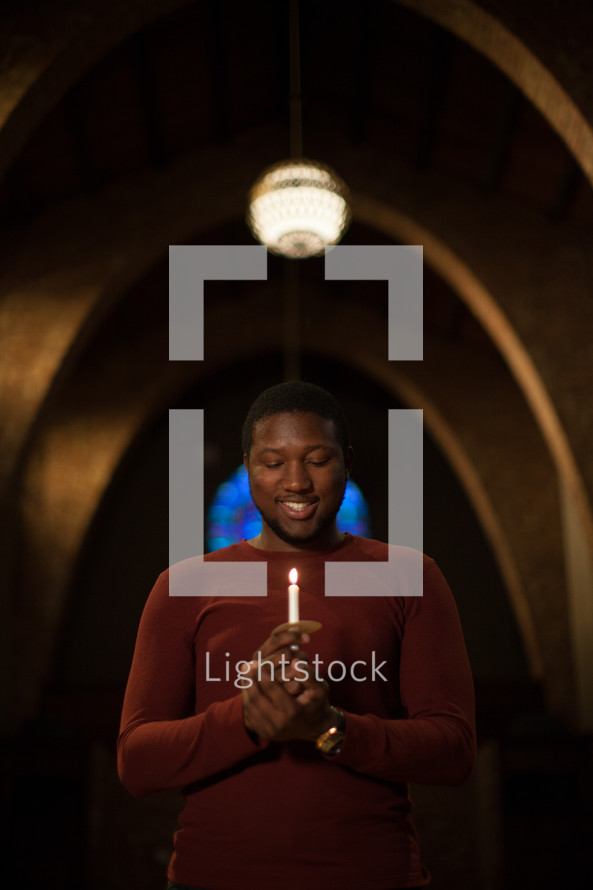 an African American man holding a candle at a Christmas Eve Service 