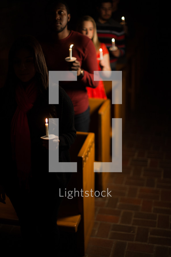 parishioners standing holding candles at a Christmas Eve service 