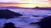 Misty mountains at sunrise: moving clouds and swirling fog create a tranquil and enchanting scene