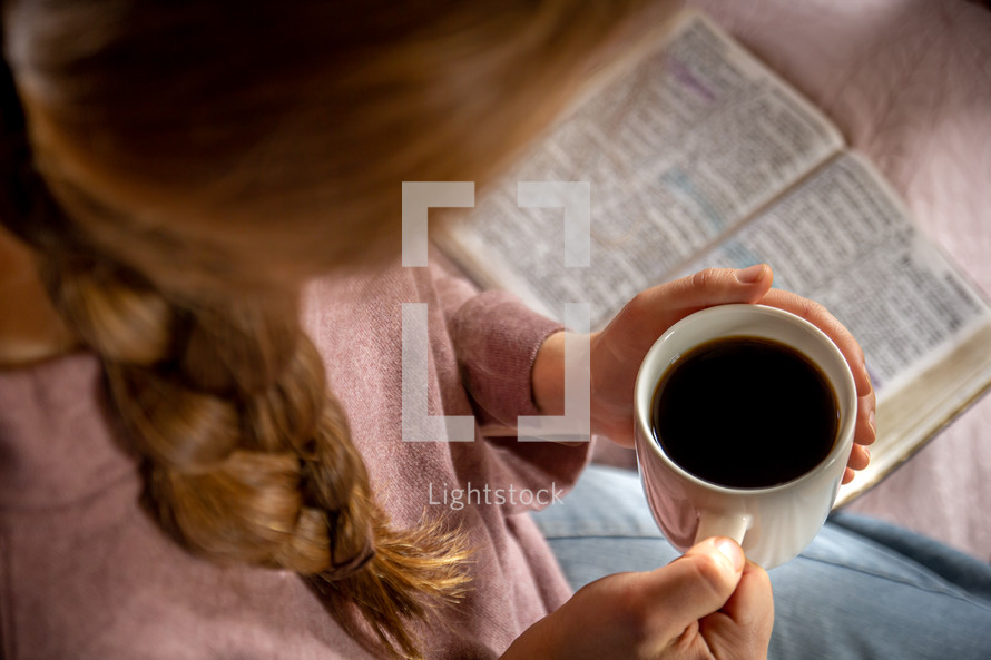 a woman holding a coffee mug with a Bible in her lap 