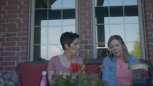 women sitting on a porch talking 