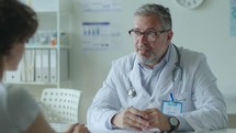 Senior Doctor Having Conversation with Patient in Clinic
