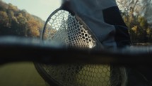 Fly fisherman’s net resting in a river during sunrise