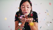 a woman blowing confetti 