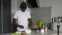 African man standing in kitchen records on cellphone new food videoblog in the morning, slow motion.