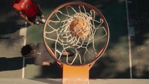 Young men playing basketball on an outdoor court on a sunny day