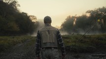 Young fly fisherman walking to a river at dawn