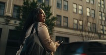 Young business woman walking around the city using her phone and laptop