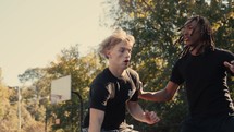 Young men playing basketball on an outdoor court on a sunny day