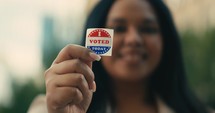 Young woman smiling with an ‘I Voted’ stickers and pin 