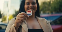 Young woman smiling with an ‘I Voted’ stickers and pin 