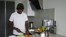 African man standing in kitchen records on cellphone new food videoblog.