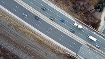 Aerial top twist shot of Gardiner Expressway in Toronto on a winter day. The drone spins as it shows the pass of vehicles across the highway. Railroad tracks are visible on the side of the traffic.