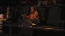 Woman sitting in armchair watching a movie at the cinema alone.