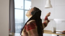 Portrait of the young African American woman wearing headphones listening to the music at home.