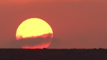 Time lapse of sun rising above moving clouds and the horizon