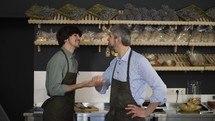 Close up portrait of happy father and son, family business owners, high five in their bakery store, looking at camera and smiling.