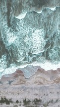 aerial view over the ocean washing onto a shore 