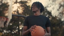 Portrait of a smiling young man playing basketball on a sunny day