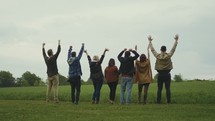 group standing together in a field with hands raised 