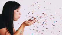 a woman blowing confetti 