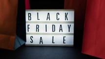 Black friday signboard with bags and blinking lights 