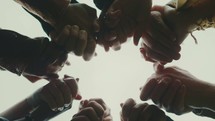 looking up into a group holding hands in prayer 