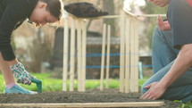 a couple planting seeds in a garden