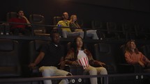 Mixed raced young couple sitting in movie theatre and watching film.