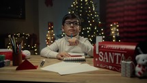 Young boy writing Christmas letter at his desk